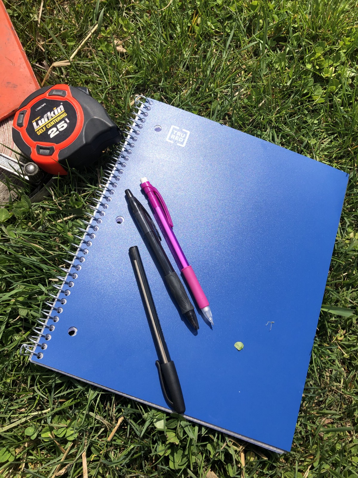 A notebook, pens, and measuring tape for garden planning