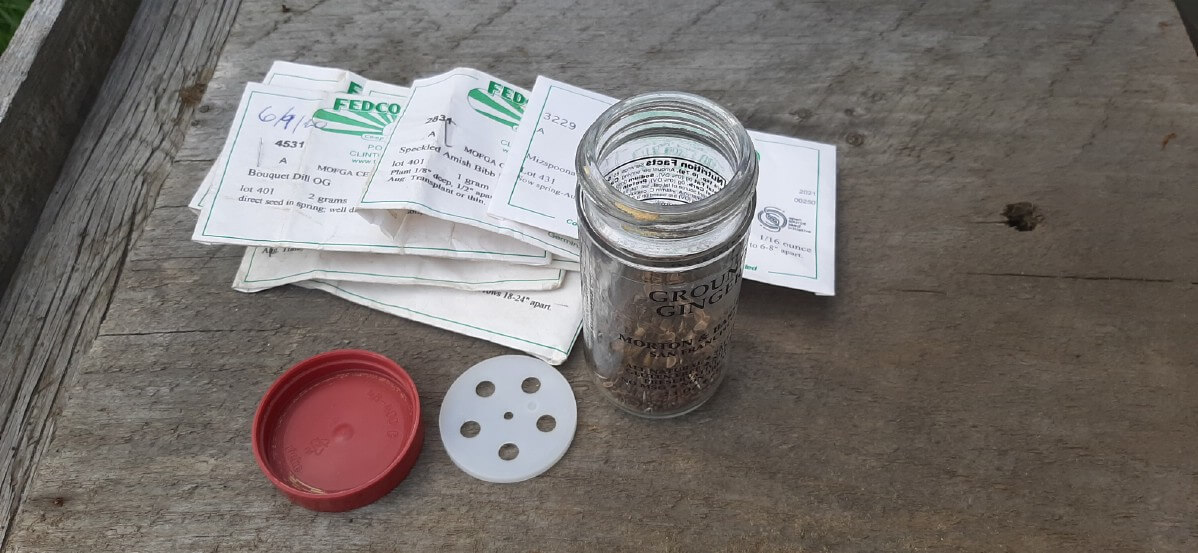 Assortment of garden seeds and a glass jar to mix them.