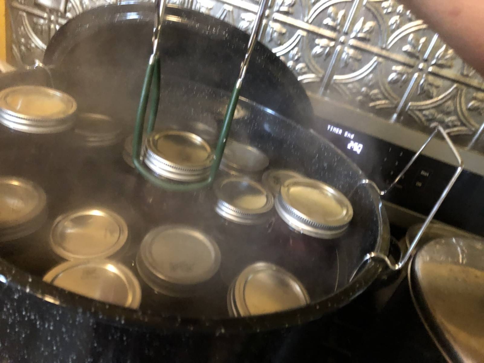 canning jar tongs lifting hot jars from water