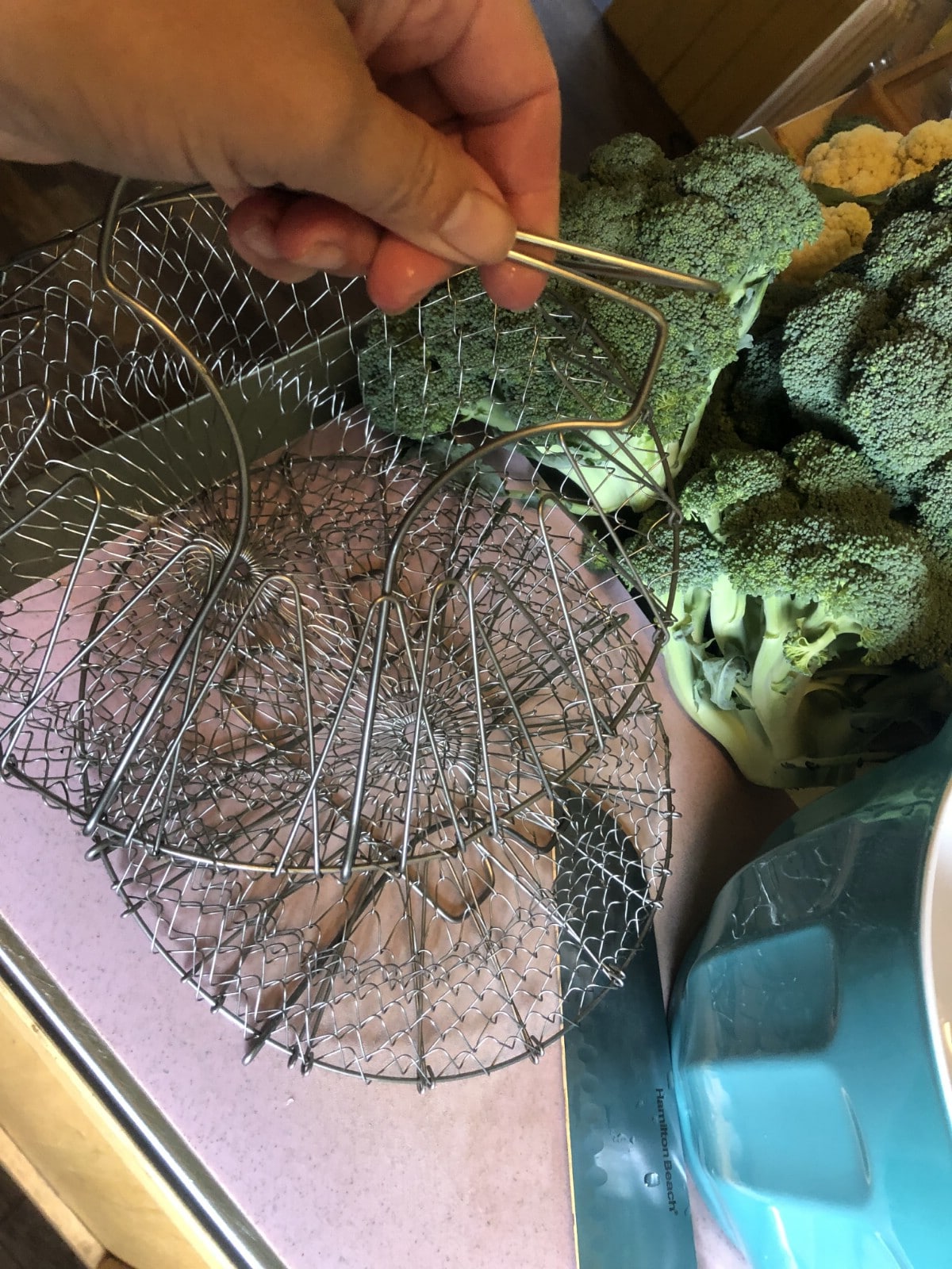 collapsible blanching baskets next to fresh broccoli heads