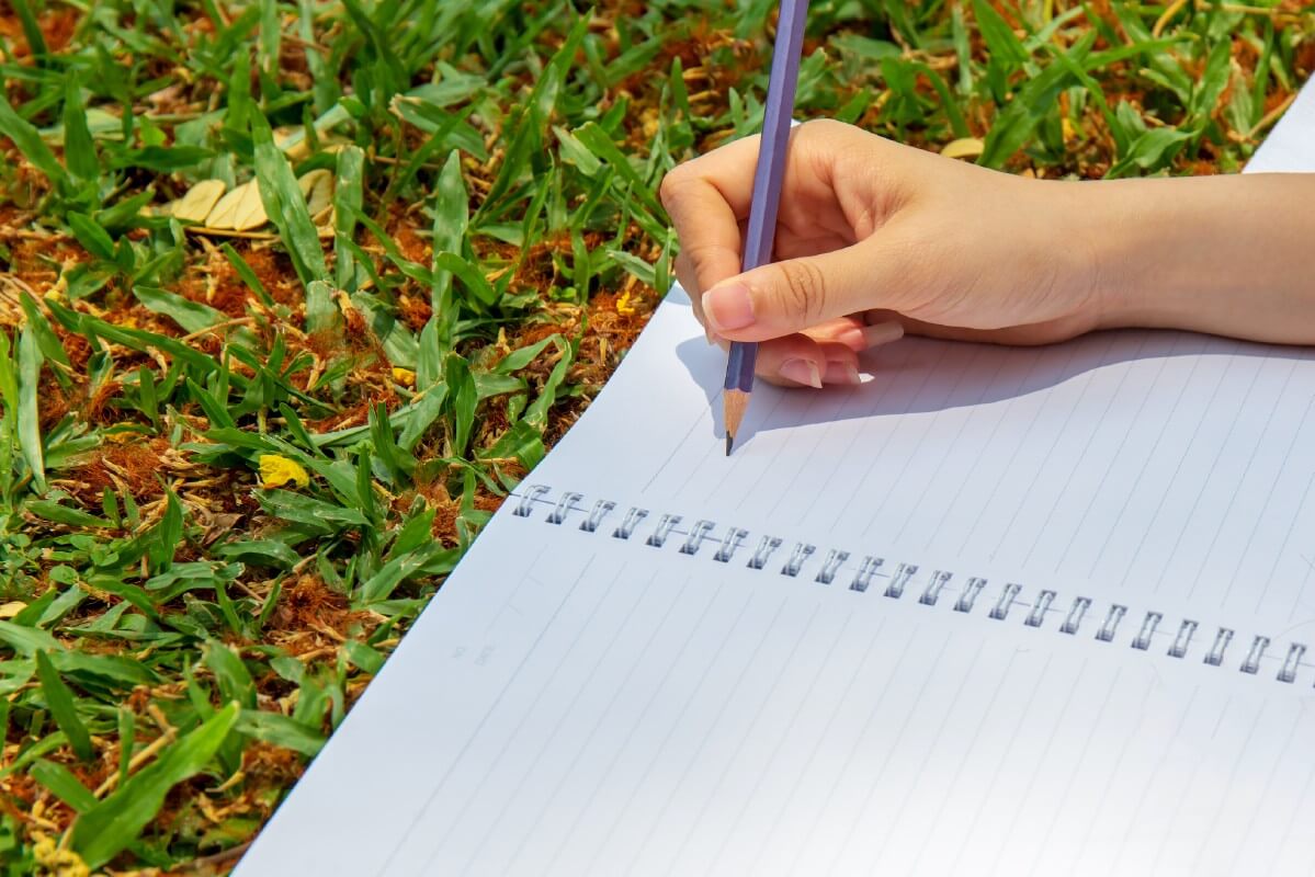 journaling in a blank notebook on the grass