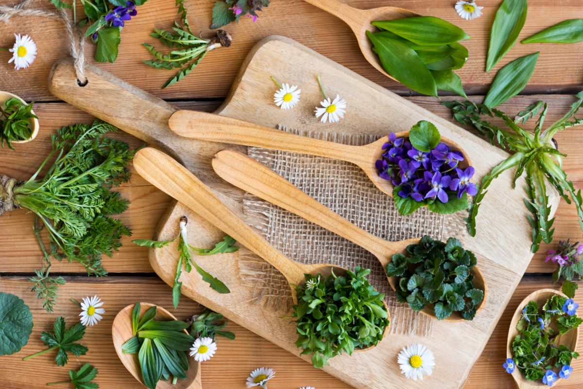 three spoons of edible flowers and herbs on a cutting board