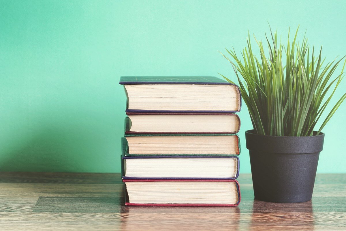 stack of books next to grassy plant