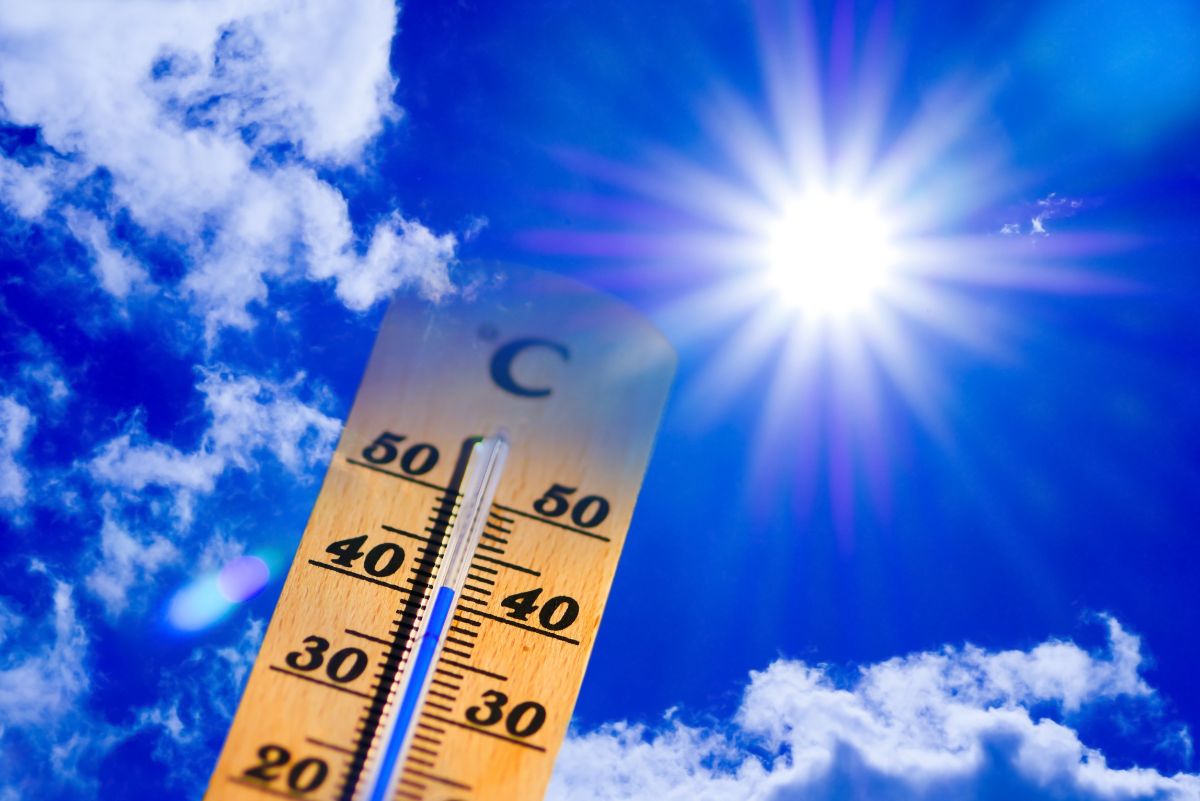 Wooden thermometer against the backdrop of intense sun and blue sky