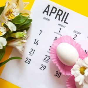 April calendar with flowers, eggs on yellow background