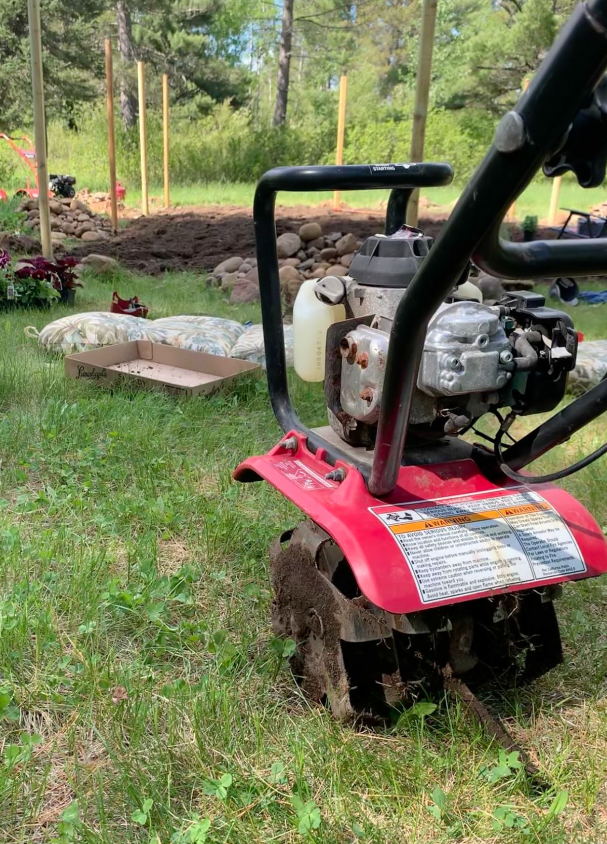 A personal-sized front tine cultivator next to fresh tilled soil