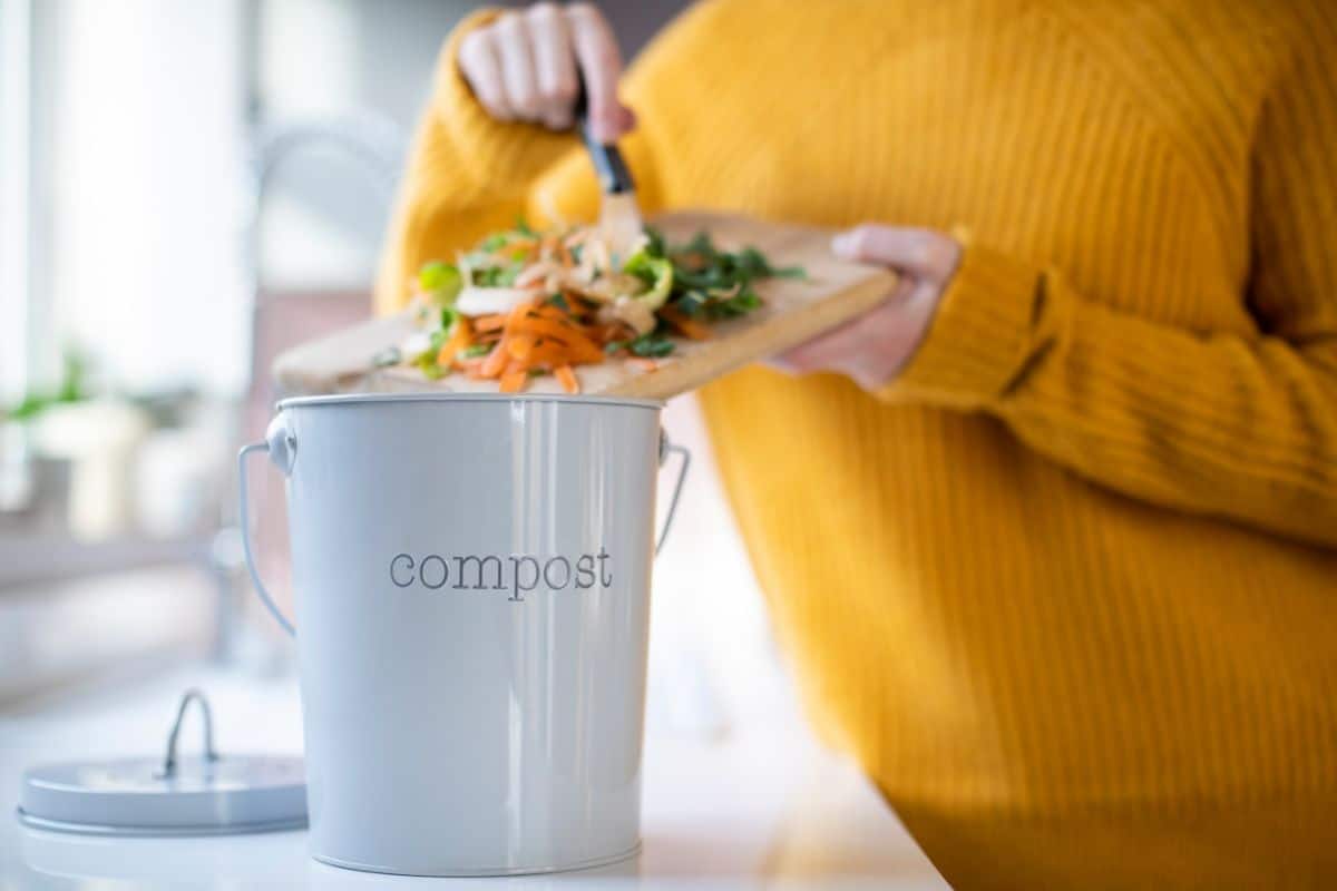 Woman scraping kitchen scraps into a compost pail