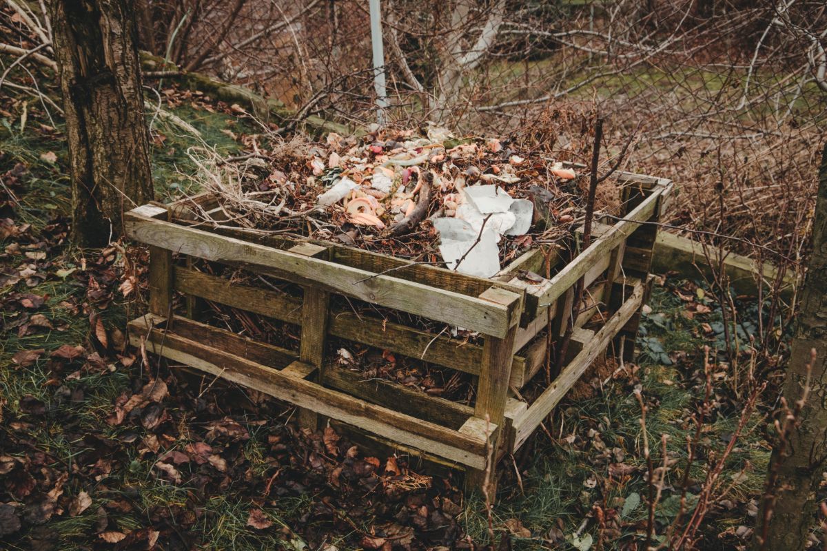 A compost bin made of pallets filled with compost and yard waste