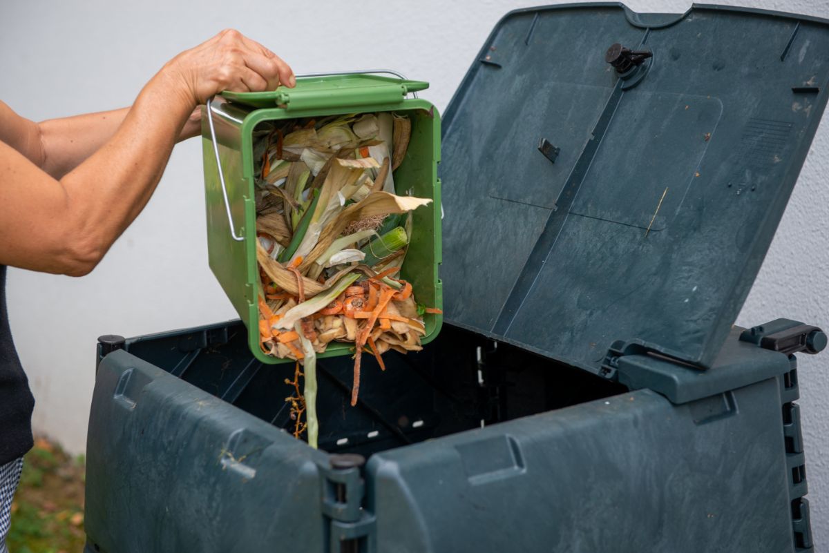 Woman dumping kitchen scraps into a compost bin
