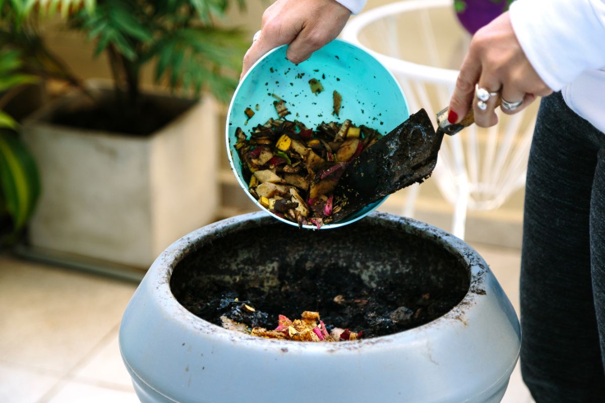 A person scraping scraps into a Bokashi compost bin