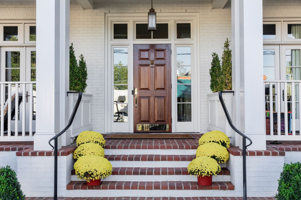 Butter-yellow potted mums on a house stairway