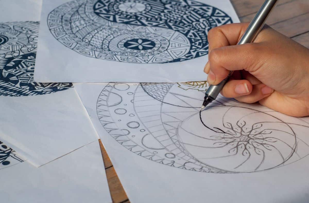 A person drawing plans for a mosaic stepping stone project