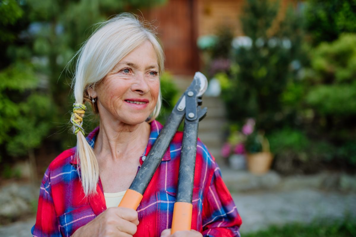 An older gardener with loppers thinking about changing her garden