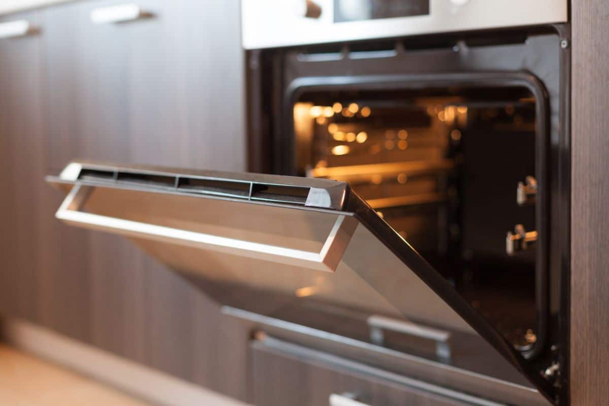 An oven with its door open to get a low temperature for drying herbs