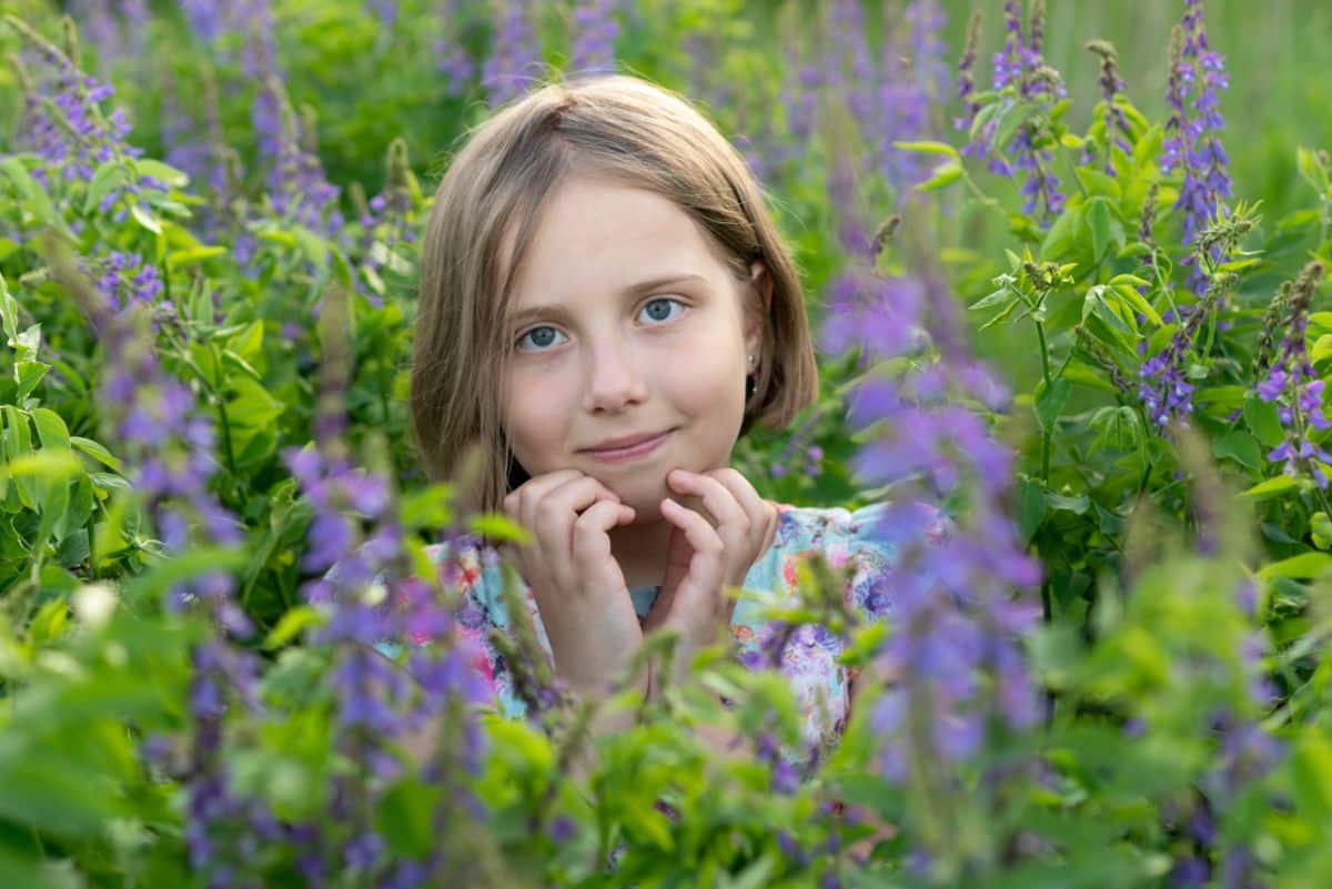 A young girl smiling in a stand of wildflowers