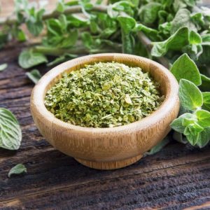 Wooden bowl of dried oregano on a table.