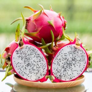 Ripe whole and halves dragon fruits on a small plate.