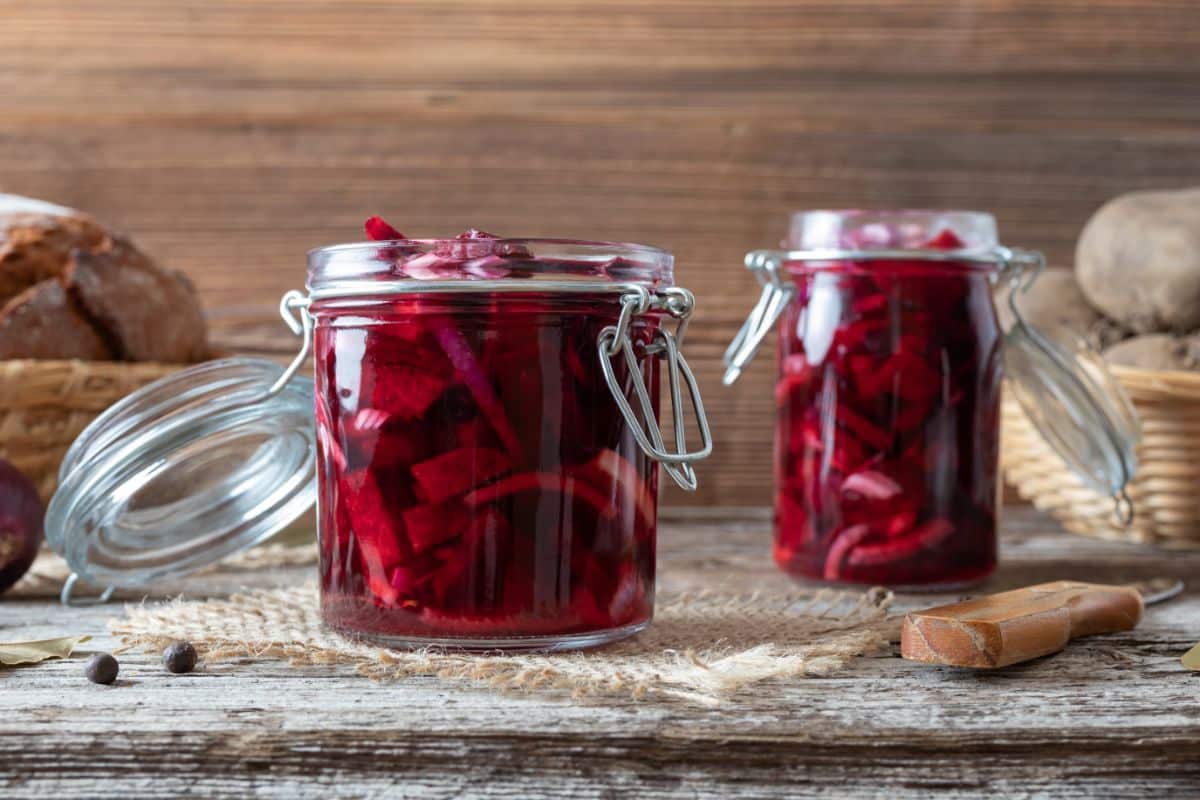 Jars of fermented pickled beets stand on a wood table
