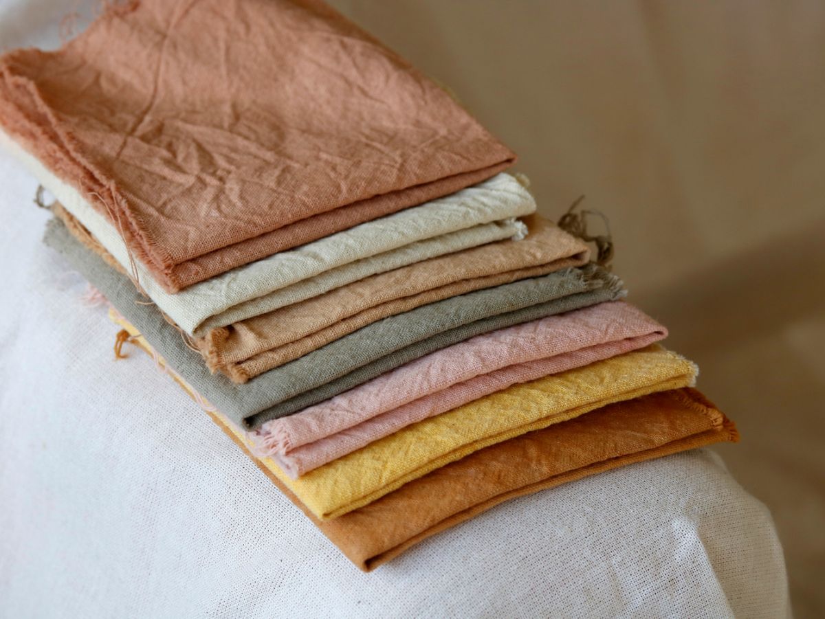 Folded and stacked fabrics dyed with natural plant dyes show off a range of colors