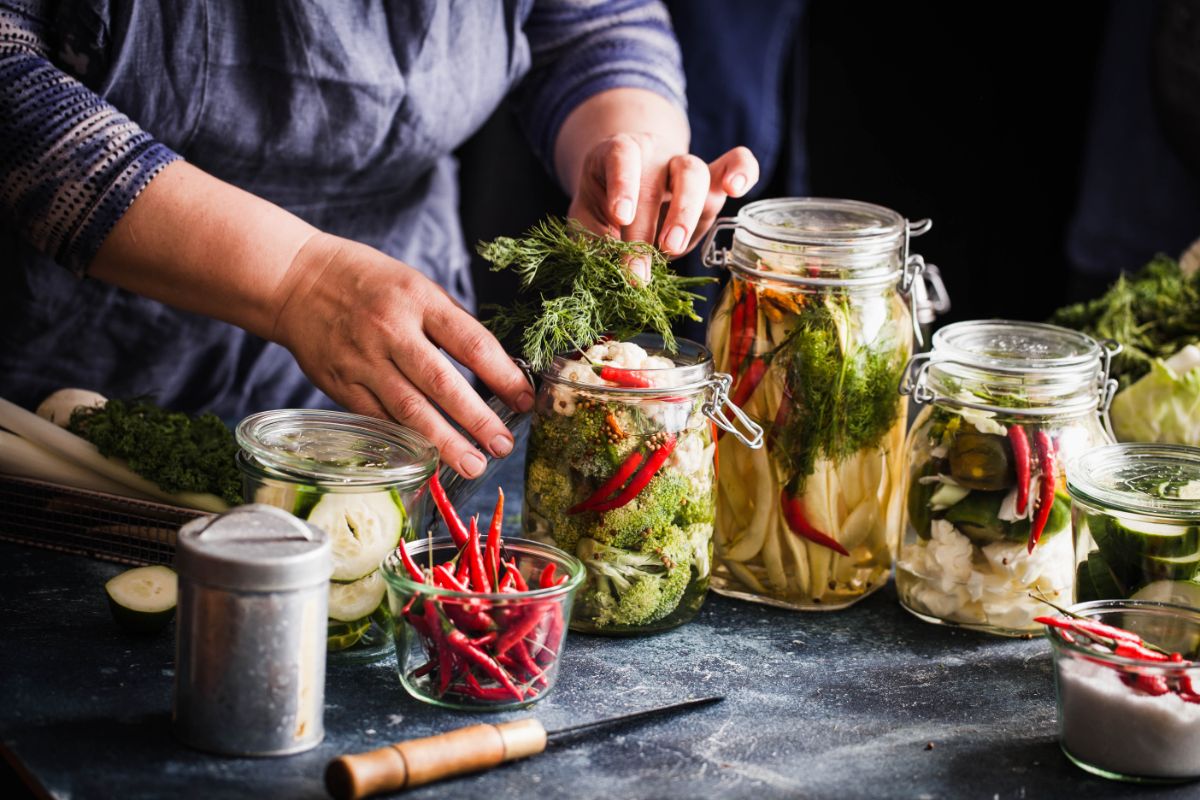 A woman prepares jars of vegetables for lact-fermentation