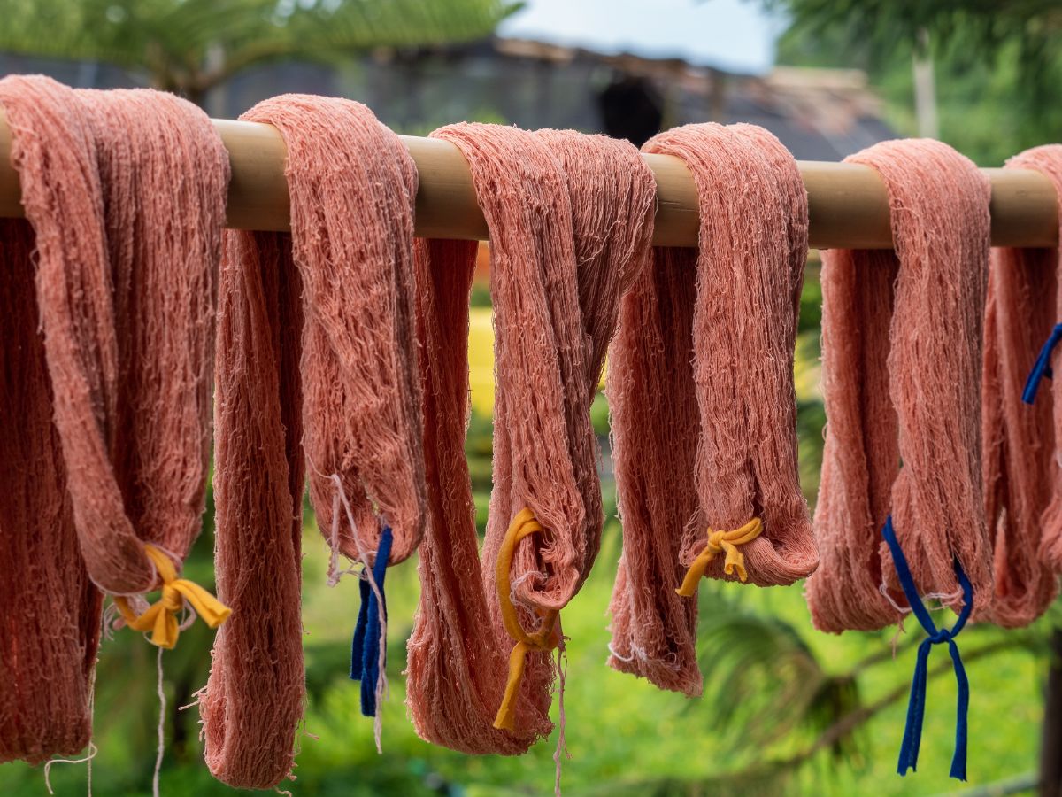Skeins of homemade red dyed yarn hang on a rod to dry