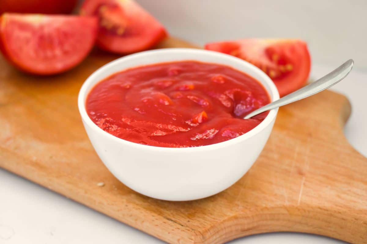 Homemade tomato ketchup offered in a bowl with a spoon for serving