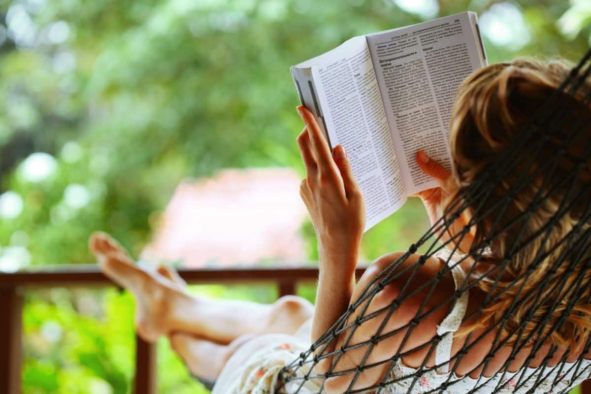 A woman relaxing with a book outside on a porch