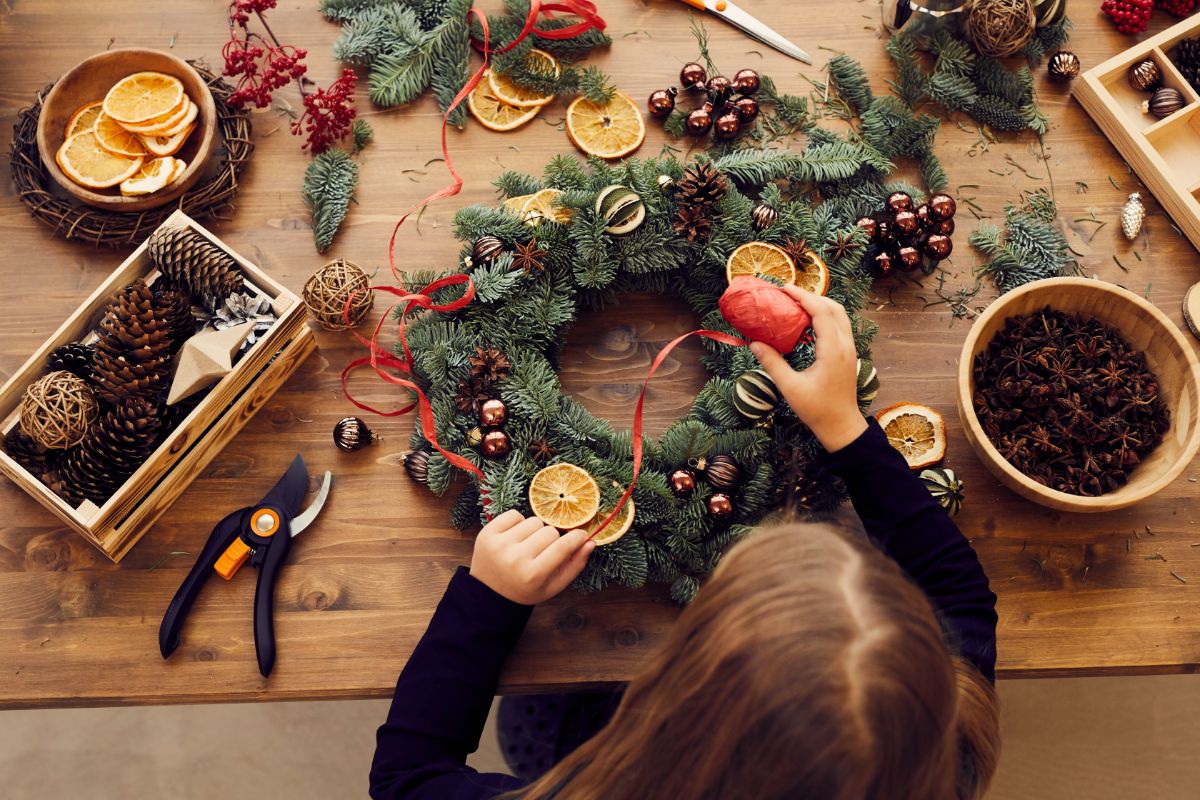 A young girl decorates a handmade Christmas wreath