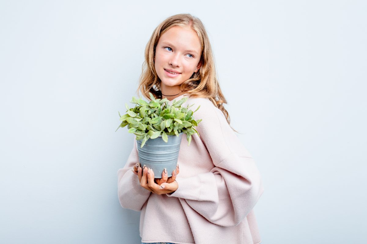 A happy girl holding a houseplant that was given as a gift.