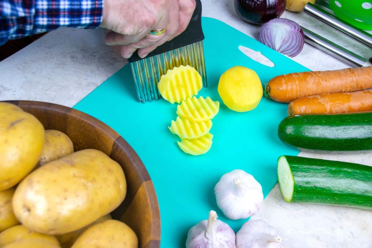 A person cutting a Snowden potato into chips