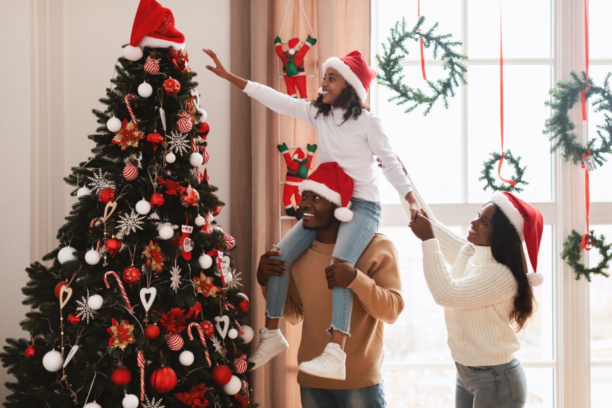 A happy family putting the topper on a happy, healthy, watered Christmas tree