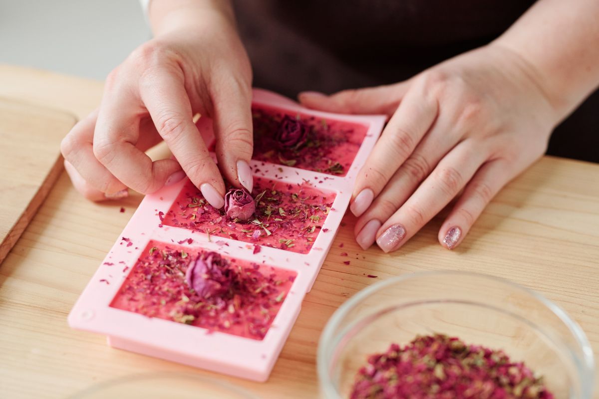 A woman making homemade rose soaps adorned with dried rosebuds