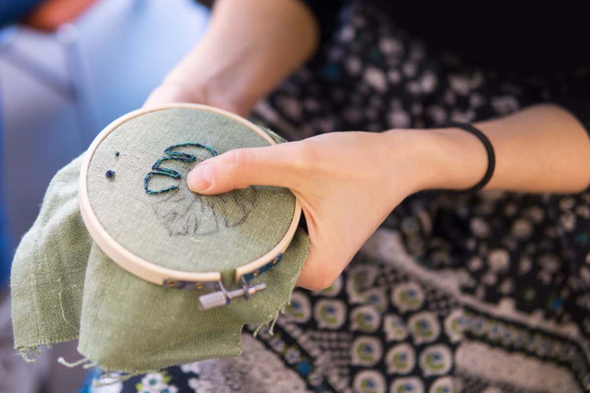 A gardener sitting with an embroidery project in the winter