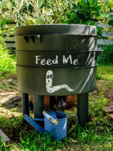 A wormery compost bin in a organic Australian garden with Feed Me worm sign.