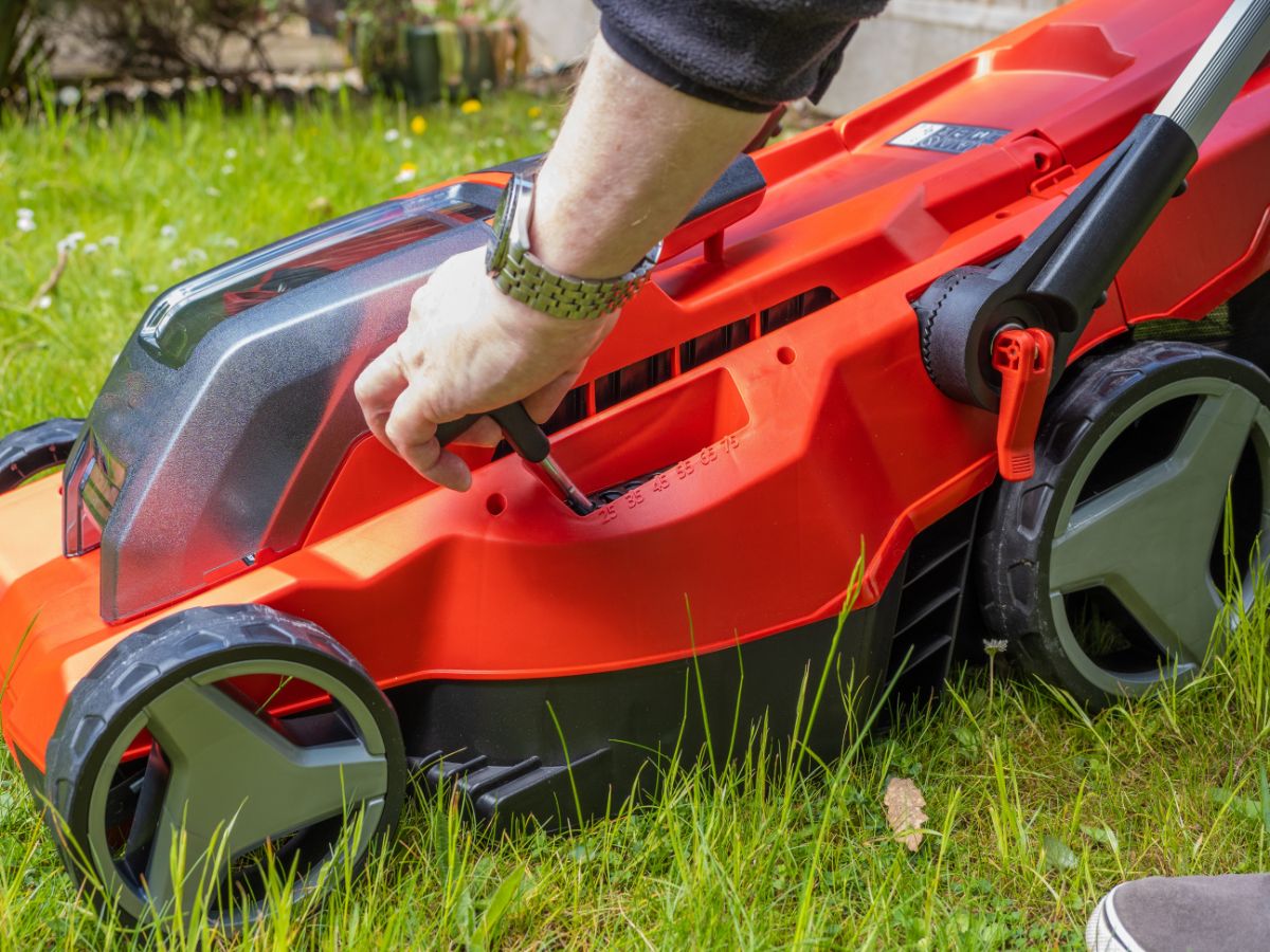 A homeowner raising the height of a mower deck