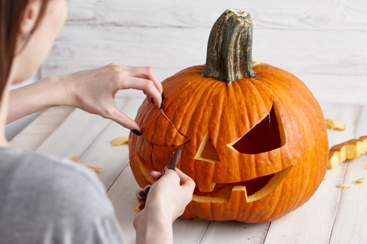 A child carves a Halloween pumpkin