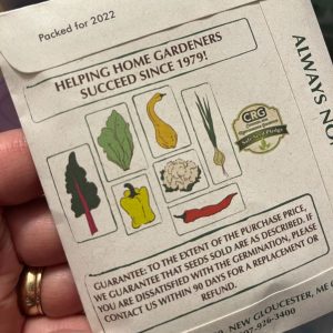 A hand holding a seed package.