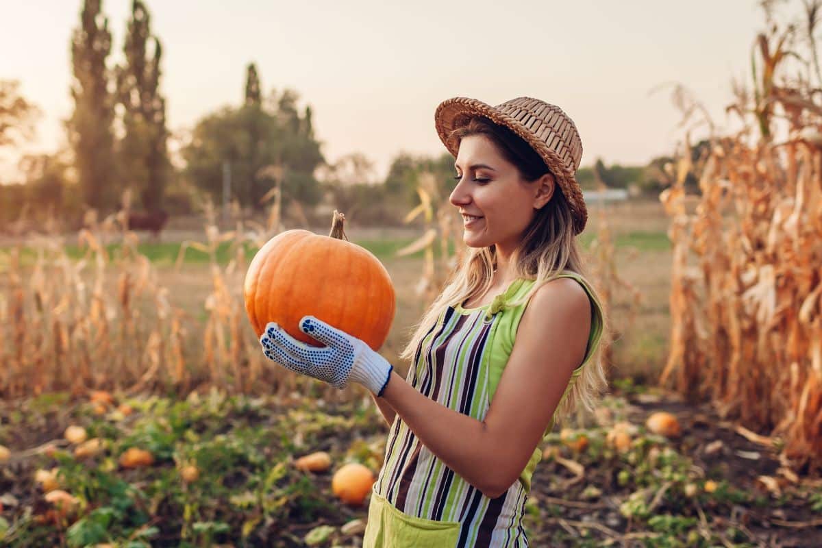 A woman smiles at her homegrown pumpkin