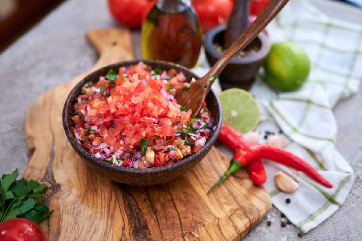 A bowl of fresh salsa sits on a table, prepared from square foot garden produce