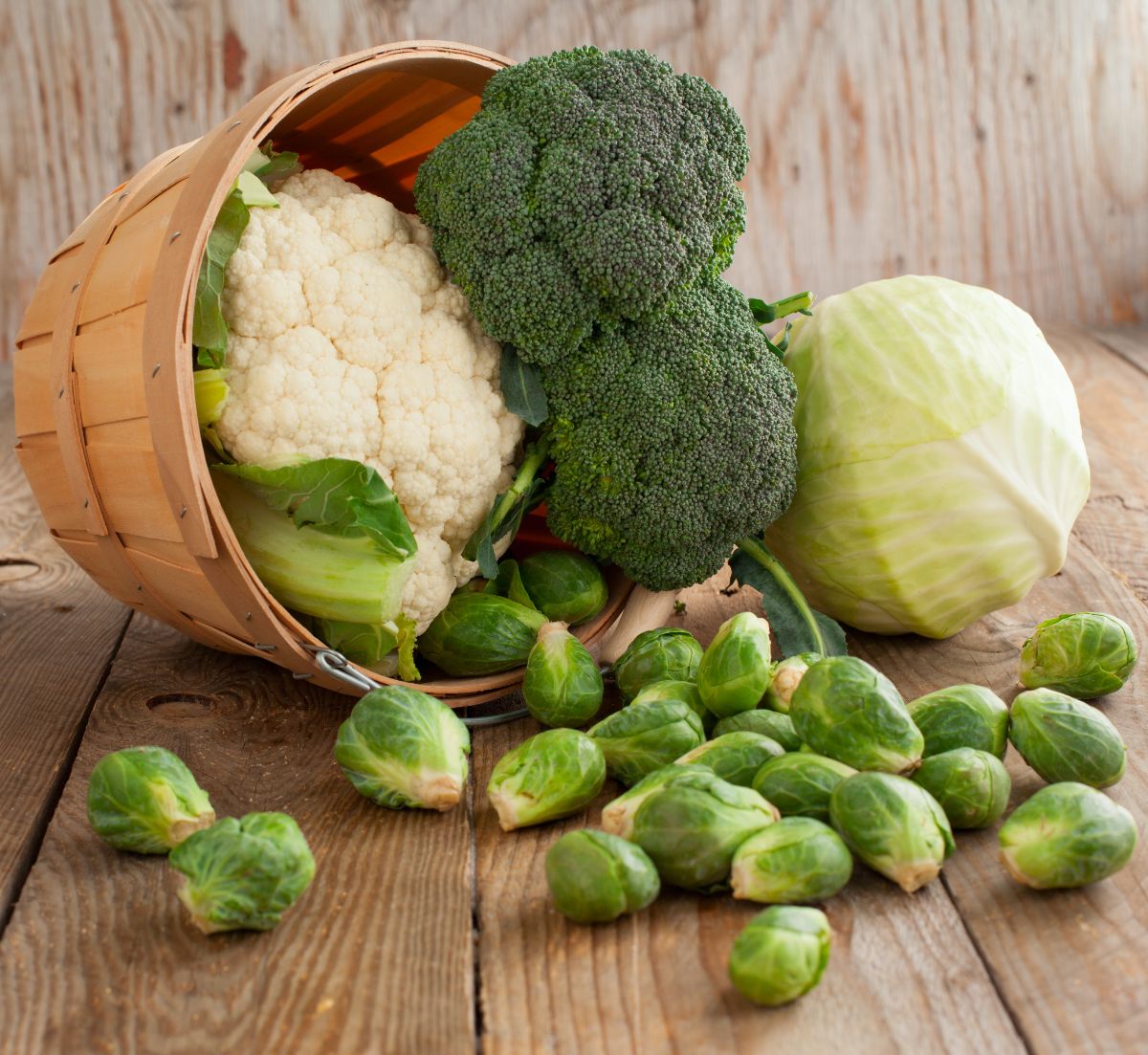 A basket full of brassica relatives spills out on a table