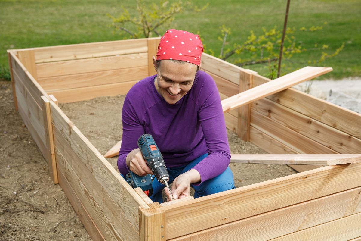 A woman drills brace pieces into a raised bed
