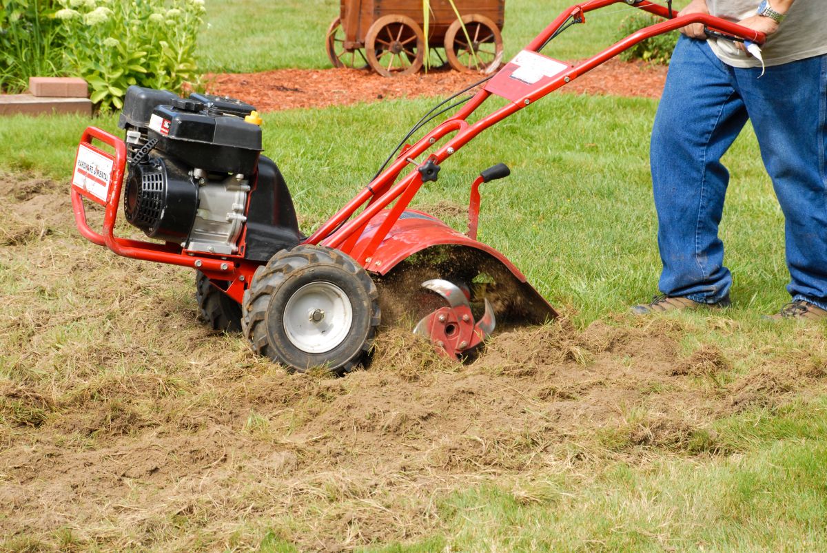 A man tills up a patch of grass to make a new garden patch