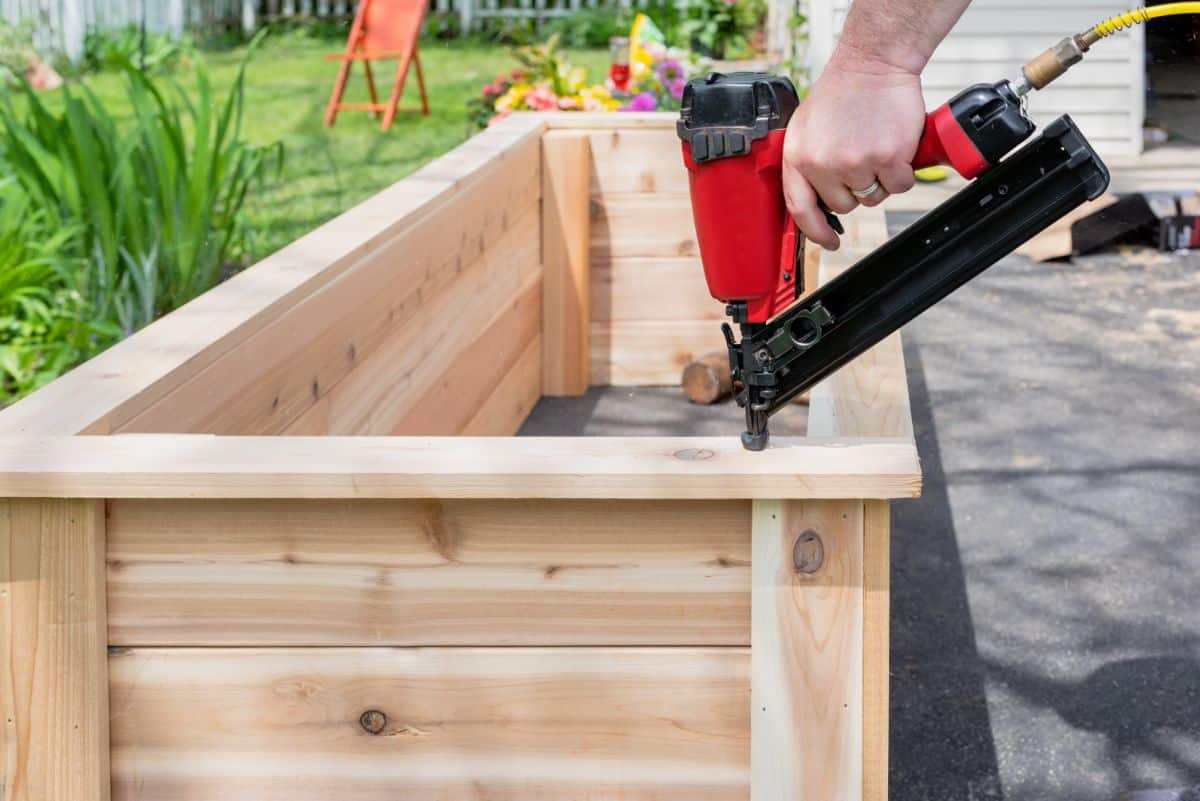 A gardener builds a raised bed for a square foot garden