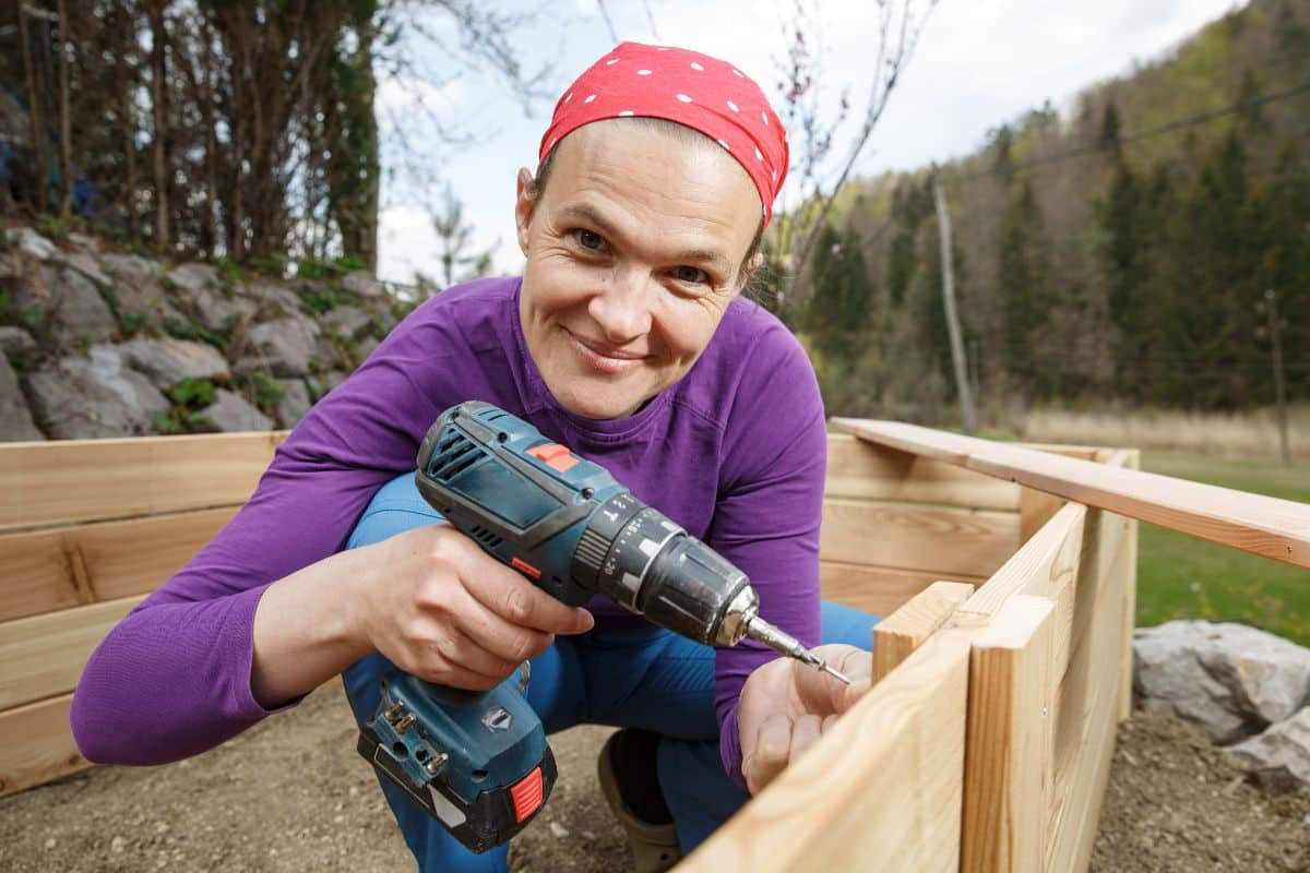 A woman builds upcycled wood frame garden beds for her square foot garden