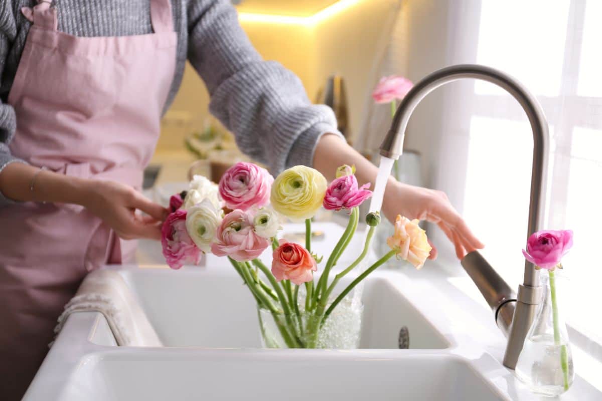 A woman fills a vase of flowers with water