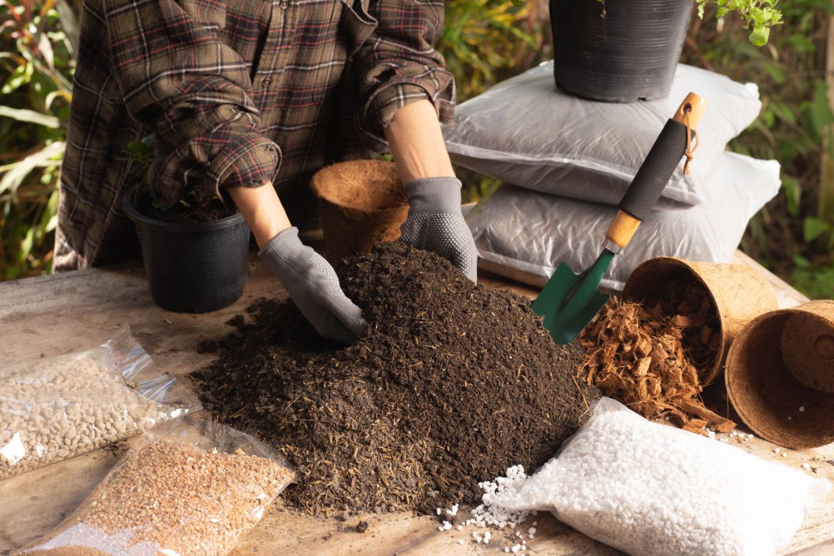 A gardener mixing compost into other soil ingredients