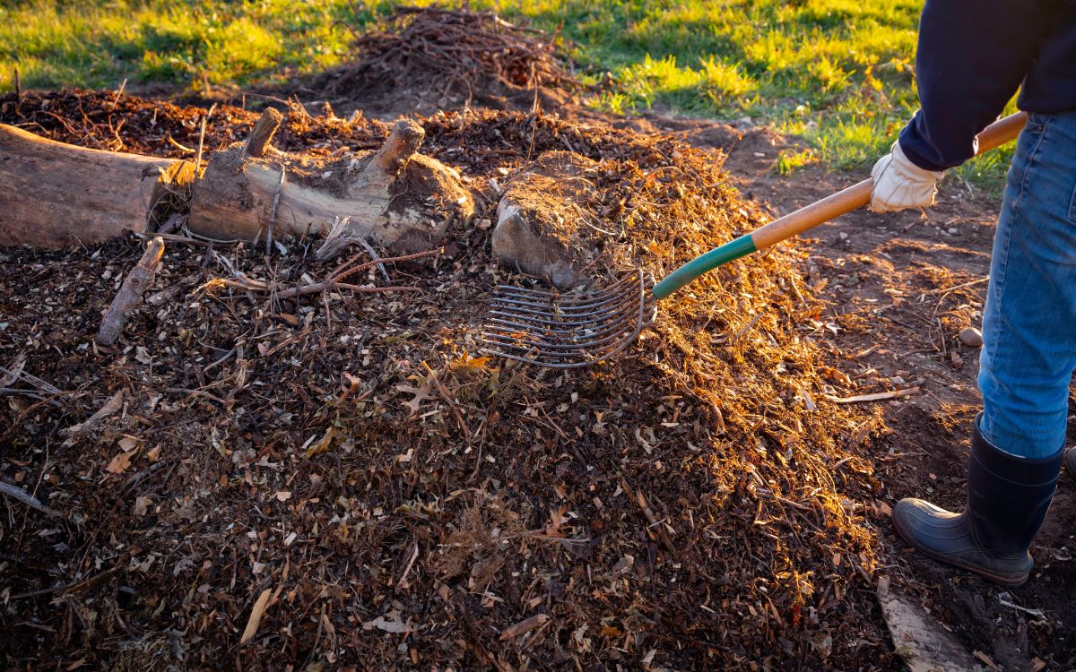 A homeowner turning a pile of compost