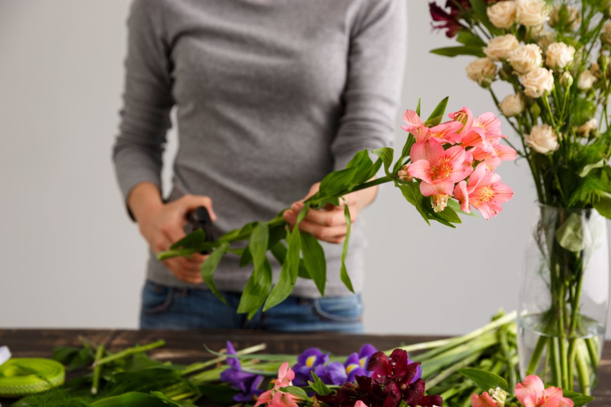 A woman makes a fresh cut on the stem of a cut flower