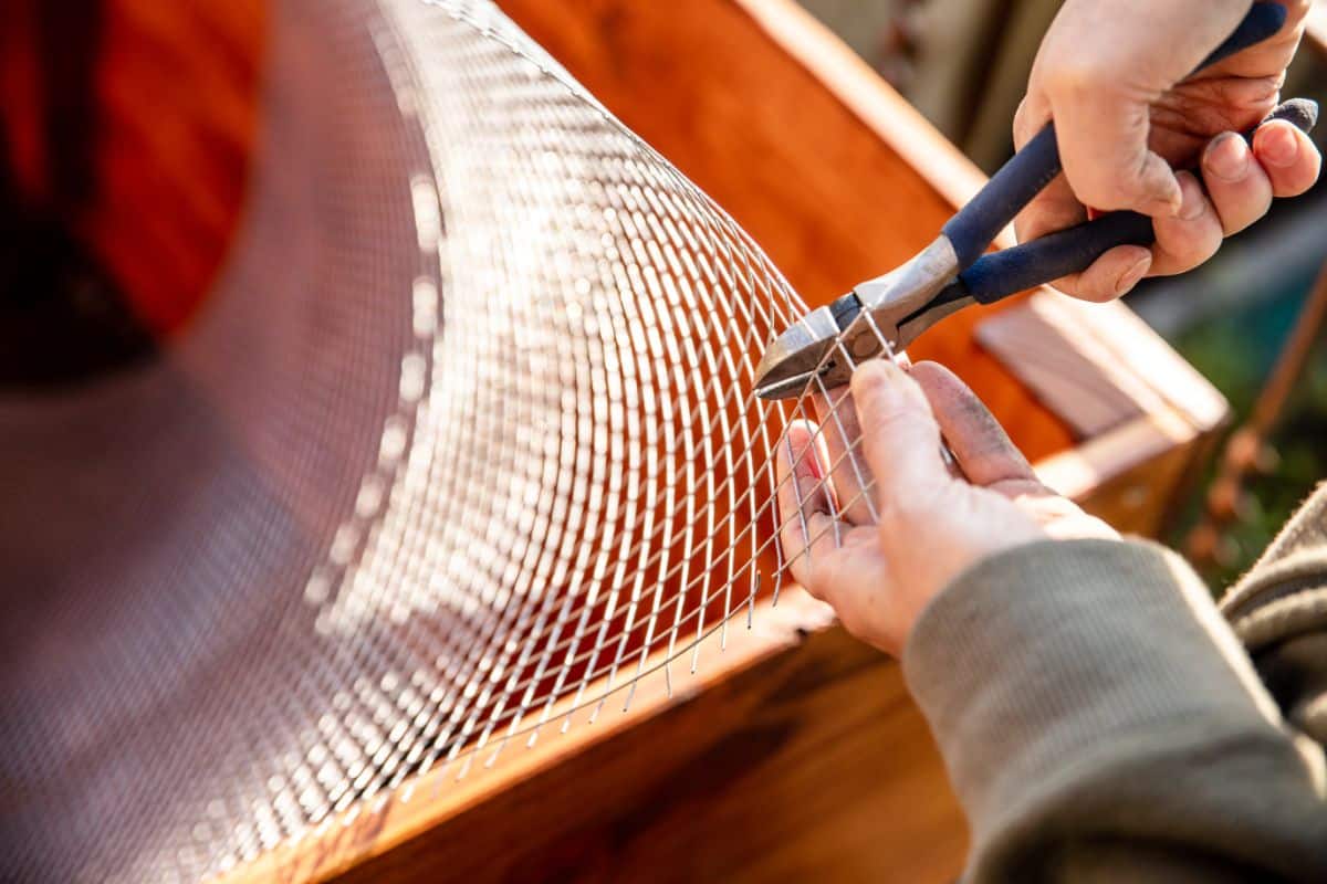 A man cuts hardware cloth for a raised bed bottom