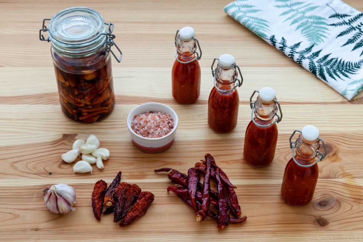 Bottles of homemade hot sauce with ingredients laid out around them